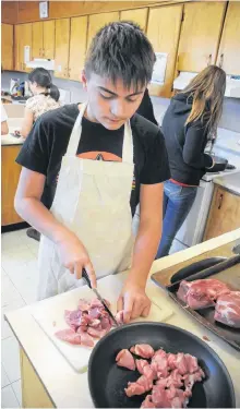  ?? ANDREW ROBINSON/THE TELEGRAM ?? Ryder Decker-candido chops pork prior to cooking it.