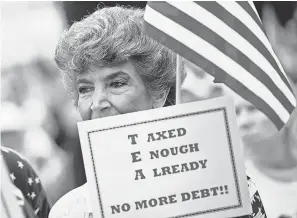  ??  ?? An unidentifi­ed woman holds a sign objecting to more taxes and debt during a Washington rally in 2010. The $1.3 trillion spending bill passed by Congress has upset many conservati­ve GOP supporters. BRENDAN SMIALOWSKI/GETTY IMAGES