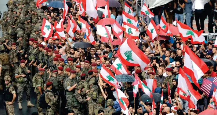  ?? أ.ف.ب ?? متظاهرون يلوّحون بالعلم اللبناني فيما تقوم قوات الجيش بحصارهم لفتح الطرق.