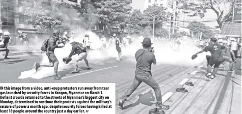  ?? Ap ?? In this image from a video, anti-coup protesters run away from tear gas launched by security forces in Yangon, Myanmar on March 1. Defiant crowds returned to the streets of Myanmar’s biggest city on Monday, determined to continue their protests against the military’s seizure of power a month ago, despite security forces having killed at least 18 people around the country just a day earlier.