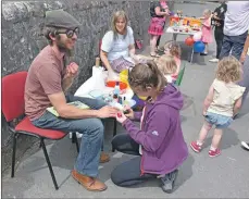  ??  ?? A parent is convinced to have his nails done while the children have their faces painted.