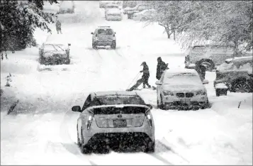  ?? ASSOCIATED PRESS ?? A SLEDDER MOVES ASIDE AS TRAFFIC HEADS DOWNHILL IN HEAVY SNOW falling Monday in Seattle. Schools closed across Washington state and the Legislatur­e canceled all hearings Monday with winter snowstorms pummeling the Northwest again as a larger weather system wreaked havoc in the region and even brought snow to Hawaii.