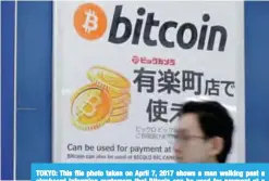  ??  ?? TOKYO: This file photo taken on April 7, 2017 shows a man walking past a signboard informing customers that Bitcoin can be used for payment at a store in Tokyo. —AFP