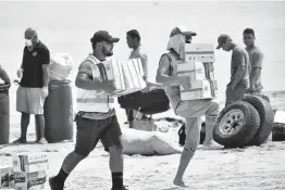  ?? MALAU MEDIA/IFRC ?? Tonga Red Cross Society’s staffers and volunteers unload boxes of noodles from the boat onto the beach April 1 in Nomuka on Ha’apai Island, Tonga.