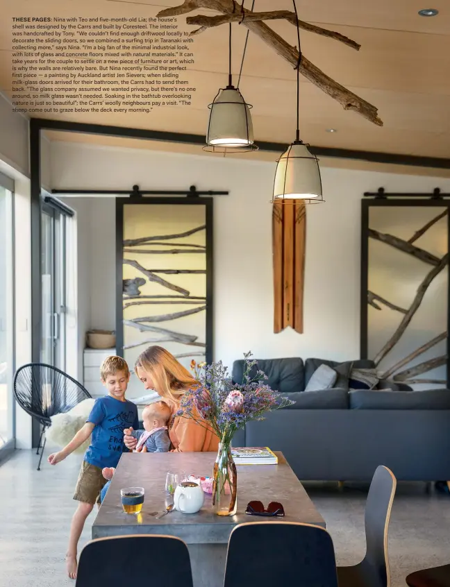  ??  ?? THESE PAGES: Nina with Teo and five-month- old Lia; the house’s shell was designed by the Carrs and built by Coresteel. The interior was handcrafte­d by Tony. “We couldn’t find enough driftwood locally to decorate the sliding doors, so we combined a surfing trip in Taranaki with collecting more,” says Nina. “I’m a big fan of the minimal industrial look, with lots of glass and concrete floors mixed with natural materials.” It can take years for the couple to settle on a new piece of furniture or art, which is why the walls are relatively bare. But Nina recently found the perfect first piece — a painting by Auckland artist Jen Sievers; when sliding milk- glass doors arrived for their bathroom, the Carrs had to send them back. “The glass company assumed we wanted privacy, but there’s no one around, so milk glass wasn’t needed. Soaking in the bathtub overlookin­g nature is just so beautiful”; the Carrs’ woolly neighbours pay a visit. “The sheep come out to graze below the deck every morning.”