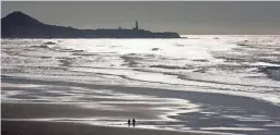  ?? AP ?? The sun shimmers over the beach with the Yaquina Head lighthouse on the horizon in Newport, Ore.