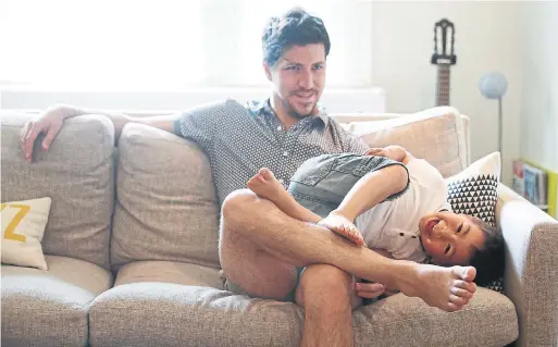  ??  ?? Osher gets some snuggles from his father, Michael. Osher’s parents are trying to foster a growth mindset, challengin­g him to learn how to face failure.