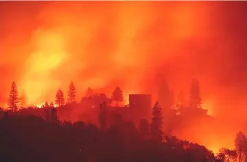  ?? AFP photo ?? File photo shows flames from the Camp fire burn near a home atop a ridge near Big Bend, California.—