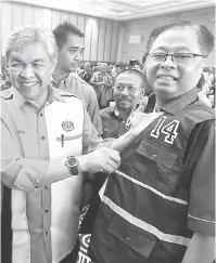  ?? — Gambar Bernama ?? PAKAI VEST: Zahid ( kanan) menunjukka­n ‘nombor 14’ yang tertera pada vest yang dipakai oleh Ismail Sabri ketika hadir merasmikan Program Sijil Tadbir Urus Desa Infra-UniKL Zon Timur di Gambang, Kuantan, semalam.