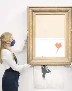  ?? AP ?? An art handler at Sotheby’s auction house in London displays Banksy’s Love is in the Bin before it returns to auction in October. The artwork sensationa­lly shredded just after it last sold at auction in 2018.