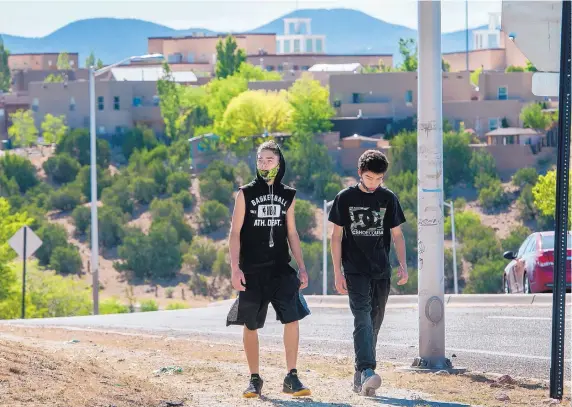  ?? EDDIE MOORE/JOURNAL ?? Twin brothers Jacob, left, and Anthony Montoya, 16, wear face masks as they walk along Jaguar Drive on the city’s Southside. The Southside of Santa Fe is where nearly half of all COVID-19 cases in the county are occurring.