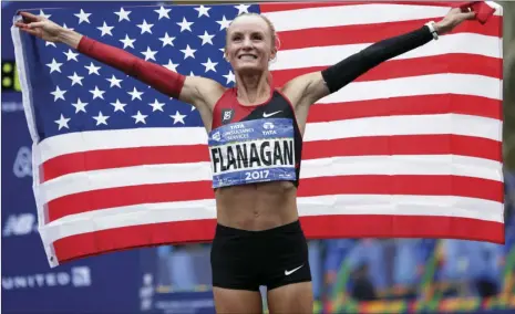  ??  ?? Shalane Flanagan of the United States poses for pictures after crossing the finish division of the New York City Marathon in New York on Sunday. AP line first in the women’s