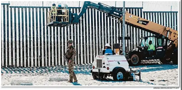  ?? ARIANA DREHSLER/GETTY-AFP ?? A Border Patrol officer stands guard Friday as work crews reinforce the border fence in San Diego. U.S. military troops are barred from conducting law enforcemen­t duties.