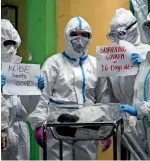  ?? AP ?? INvINCIBLE INfANT: Health workers wearing protective suits hold signs beside a 16-day-old baby, nicknamed ‘Kobe’, who recovered from Covid-19 as he is discharged from the National Children’s Hospital in Quezon city, Metro Manila, on Tuesday. —