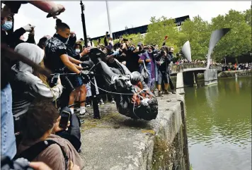  ?? BEN BIRCHALL — PA VIA AP ?? Protesters throw a statue of slave trader Edward Colston into Bristol Harbour during a Black Lives Matter protest rally in Bristol, England, on Sunday in response to the death of George Floyd while being detained by police in Minneapoli­s.