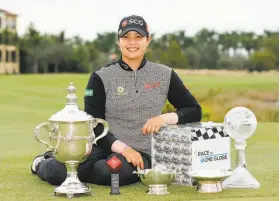  ?? Michael Reaves / Getty Images ?? Thailand’s Ariya Jutanugarn sits with her trophies that include Player of the Year, the Vare scoring title and the Race to the CME Globe points title.