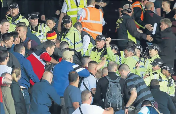  ??  ?? Baton-wielding police had to move in to separate supporters at the Cricket Field end of Burnley’s Turf Moor Stadium.