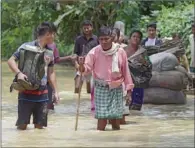  ?? (AFP) ?? People wade through the flood waters in Nagaon district of India’s Assam state on Wednesday.