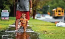  ?? Mark Mulligan / Staff photograph­er ?? Meredith Mire, 15 months, doesn’t let a puddle deter her fun along Willowbend Boulevard with her grandfathe­r Darrell Dullnig.