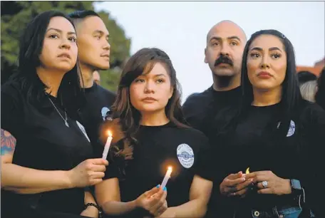  ?? Gary Coronado Los Angeles Times ?? EL MONTE POLICE Det. Nicole Lona, left, Officer Dennis Chiu, Officer Maribel Rojas, Officer Raul Vega and Sgt. Arlen Castillo at the vigil. Many in attendance wore black T-shirts with the slain officers’ names across the back and the words “Fallen but not forgotten.”