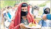  ?? PARDEEP PANDIT/HT ?? ■
Migrant labourers getting food outside a reservatio­n centre before boarding a train in Jalandhar on Sunday.