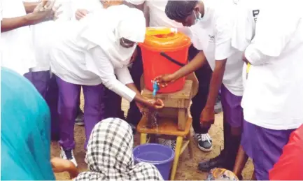  ?? Photo Ikechukwu Ibe ?? Students of Government Secondary School Wuse, Abuja, show children of internally displaced persons at Durumi IDP Camp how to wash their hands, during the global hand washing day sponsored by Exxon mobil in Abuja yesterday.