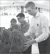  ?? Photo submitted by Palliser Regional Schools ?? Students (from left) Jaret Carnduff, Tristan Inaba and Justin Bergen place their wreaths at the front of the assembly during a Remembranc­e Day ceremony at County Central High School.