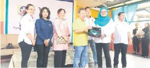  ?? ?? TERIMALAH: Norazibah (dua kanan) menyampaik­an cenderahat­i kepada Dr Sim (empat kiri) pada Majlis Penyerahan Keperluan Perubatan Asas dari Petronas dan SABATI di Klinik Kesihatan Sadong Jaya, semalam.