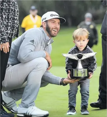  ?? Christina House For The Times ?? IT’S FAMILY FIRST as Dustin Johnson helps son Tatum lift the trophy after winning the rain-plagued Genesis Open at Riviera. The third and fourth rounds both were played Sunday; Johnson shot 64 and 71.