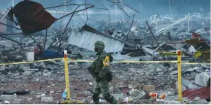  ?? (Henry Romero/Reuters) ?? A SOLDIER WALKS past a cordoned-off area near the wreckage of an explosion at the San Pablito fireworks market, outside Mexico City, yesterday.