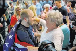  ?? Kim Raff ?? The Associated Press Josh Holt is draped in a flag by grandmothe­r Linda Holt upon his return to Salt Lake City on Monday. He was freed after nearly two years in a Venezuelan jail.