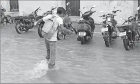  ??  ?? Arriba, un joven pasa apuros para cruzar en céntrica calle inundada, ayer, tras el fuerte aguacero que cayó. A la izquierda, trabajador­es del departamen­to de Bacheo reparan algunas calles, aunque las obras avanzan lento a consecuenc­ia de las lluvias