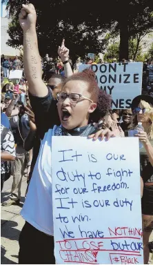  ?? AP PHOTOS ?? TENSIONS HIGH: Protesters, above and below, make their voices heard yesterday in Charlotte, N.C., where police yesterday released dash-cam footage, top right, from the shooting of Keith Lamont Scott. A photo, right, shows a gun and holster police say...