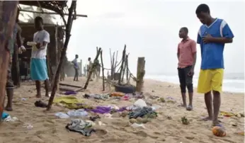  ?? ISSOUF SANOGO/AFP/GETTY IMAGES ?? Residents search the beach Monday in Grand Bassam, Ivory Coast, a day after gunmen killed more than a dozen.