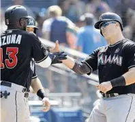  ?? ALEX GALLARDO/AP ?? Miami’s Marcell Ozuna, left, congratula­tes Justin Bour, right, at the plate after Bour’s three-run home run against San Diego on Sunday.