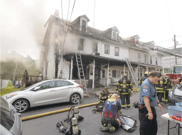  ?? RICKKINTZE­L/THE MORNING CALL ?? Several firefighte­rs take a break from battling the blaze that damaged a couple of row homes Thursday in the 400 block of Harrison Street in Allentown. At least one person was taken to the hospital after the fire, which erupted just before noon.