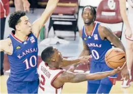  ?? GARETT FISBECK/AP ?? Oklahoma’s Umoja Gibson (2) hits a shot against Kansas’ Jalen Wilson (10) while Kansas’ Marcus Garrett looks on during a game on Jan. 23 in Norman, Okla.