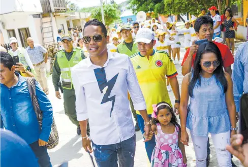  ?? FOTOS ORLANDO AMADOR ?? El delantero Carlos Bacca Ahumada caminando junto a su hija y su esposa por la calle que lleva su nombre y que se inauguró ayer.