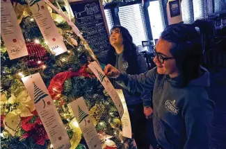  ?? BILL LACKEY / STAFF ?? Alexis Hanson, left, and Johnny Gibson, both servers at O’conners Irish Pub, 2200 N. Limestone St., look over the tags on the Salvation Army’s Angel Tree at the restaurant, Wednesday.