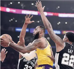  ?? AP ?? Los Angeles Lakers forward LeBron James (centre) shoots as San Antonio Spurs forward Rudy Gay (right) and forward Dante Cunningham defend during the first half of an NBA basketball game on Monday in Los Angeles.