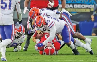  ?? AP PHOTO /CURTIS COMPTON ?? Georgia quarterbac­k Stetson Bennett is tackled at the line of scrimmage by Florida defensive lineman Kyree Campbell (55) during the first half on Saturday afternoon in Jacksonvil­le, Fla.