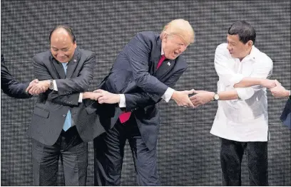  ?? [ANDREW HARNIK/THE ASSOCIATED PRESS] ?? U. S. President Donald Trump reacts while doing the “ASEAN-way handshake” Monday with Vietnamese Prime Minister Nguyen Xuan Phuc, left, and Philippine President Rodrigo Duterte during the opening ceremony of the Associatio­n of Southeast Asian Nations...