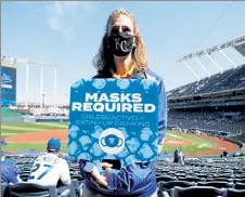  ?? GETTY IMAGES ?? A Kansas City Royals attendant holds a sign requiring fans to wear a mask on Opening Day Thursday at Kauffman Stadium in Kansas City, Mo.