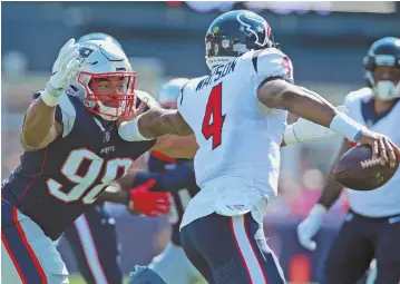  ?? STAFF PHOTO BY MATT WEST ?? ELUSIVE: Texans quarterbac­k Deshaun Watson fends off Pats defensive lineman Trey Flowers during Sunday's game.