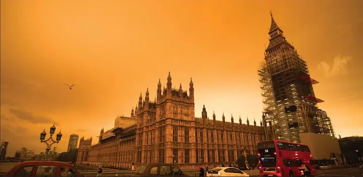  ??  ?? Weird weather over Westminste­r: The Houses of Parliament and a scaffoldin­g-covered Queen Elizabeth tower containing Big Ben are seen against the orange sky