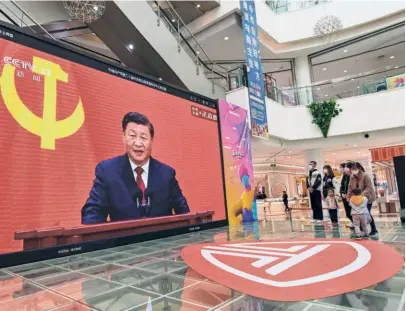  ?? ?? PEOPLE WATCH a live broadcast of President Xi Jinping speaking during the introducti­on to the Communist Party of China’s Politburo Standing Committee, on a screen at a shopping mall in Qingzhou in Shandong province on October 23.
HU JINTAO is escorted out of his seat next to Chinese President Xi Jinping and outgoing premier Li Keqiang at the closing ceremony of the Congress. He exited even as Xi took over for a precedentd­efying third term.