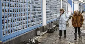  ?? DANIEL COLE / ASSOCIATED PRESS ?? Women walk by the “Memory wall of fallen defenders of Ukraine in Russia-ukrainian war” in downtown Kyiv, Ukraine, on Tuesday.