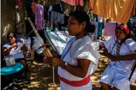  ?? ?? Wiwa women, in their traditiona­l white dress, spin the yarn to weave handbags in the Indigenous centre at Riohacha, Colombia