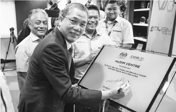  ??  ?? Fadillah signing the plaque to mark the official launching of the myBIM Centre in Kuala Lumpur. — Bernama photo