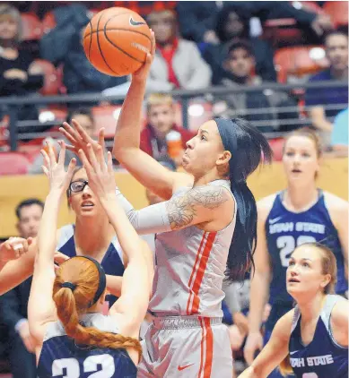  ?? JIM THOMPSON/JOURNAL ?? New Mexico’s Cherise Beynon, center, shoots over a host of Utah State players during the Lobos’ victory Wednesday night in the Pit. Beynon had only four points, but led the team with 12 assists and three steals.